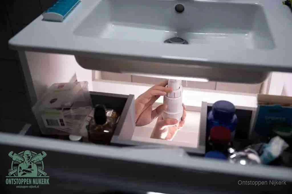Een pompfles met zeep boven een wastafel, de heet water en afwasmiddel-methode om een vetprop in de afvoer los te maken in Nijkerk