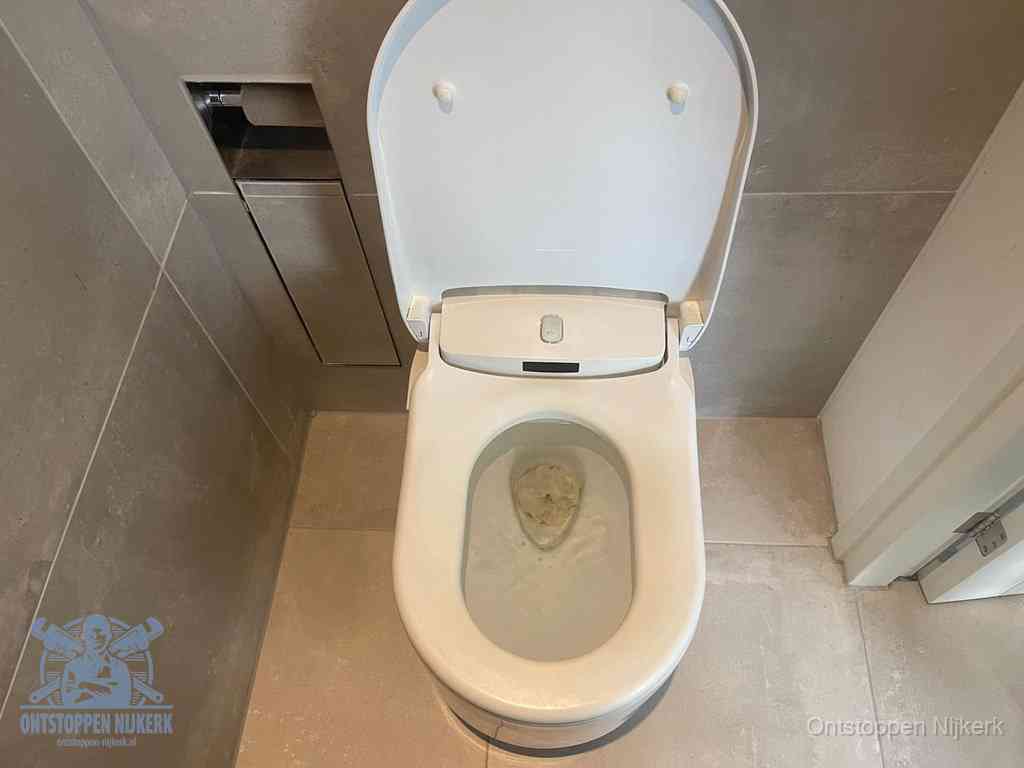 Een wit hangtoilet waarin een prop wc-papier op het water blijft drijven, een duidelijk signaal van een verstopte wc in Nijkerk