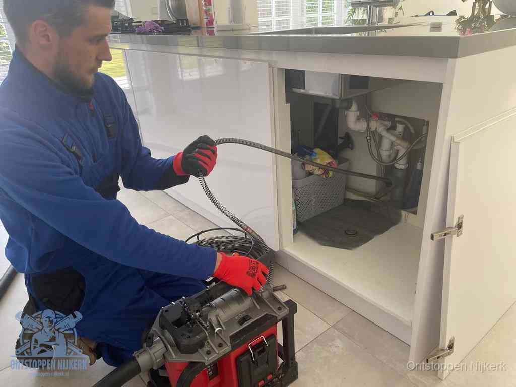 Een monteur reinigt de keukenafvoer grondig met een veermachine om terugkerende gootsteenverstoppingen te voorkomen in Nijkerk