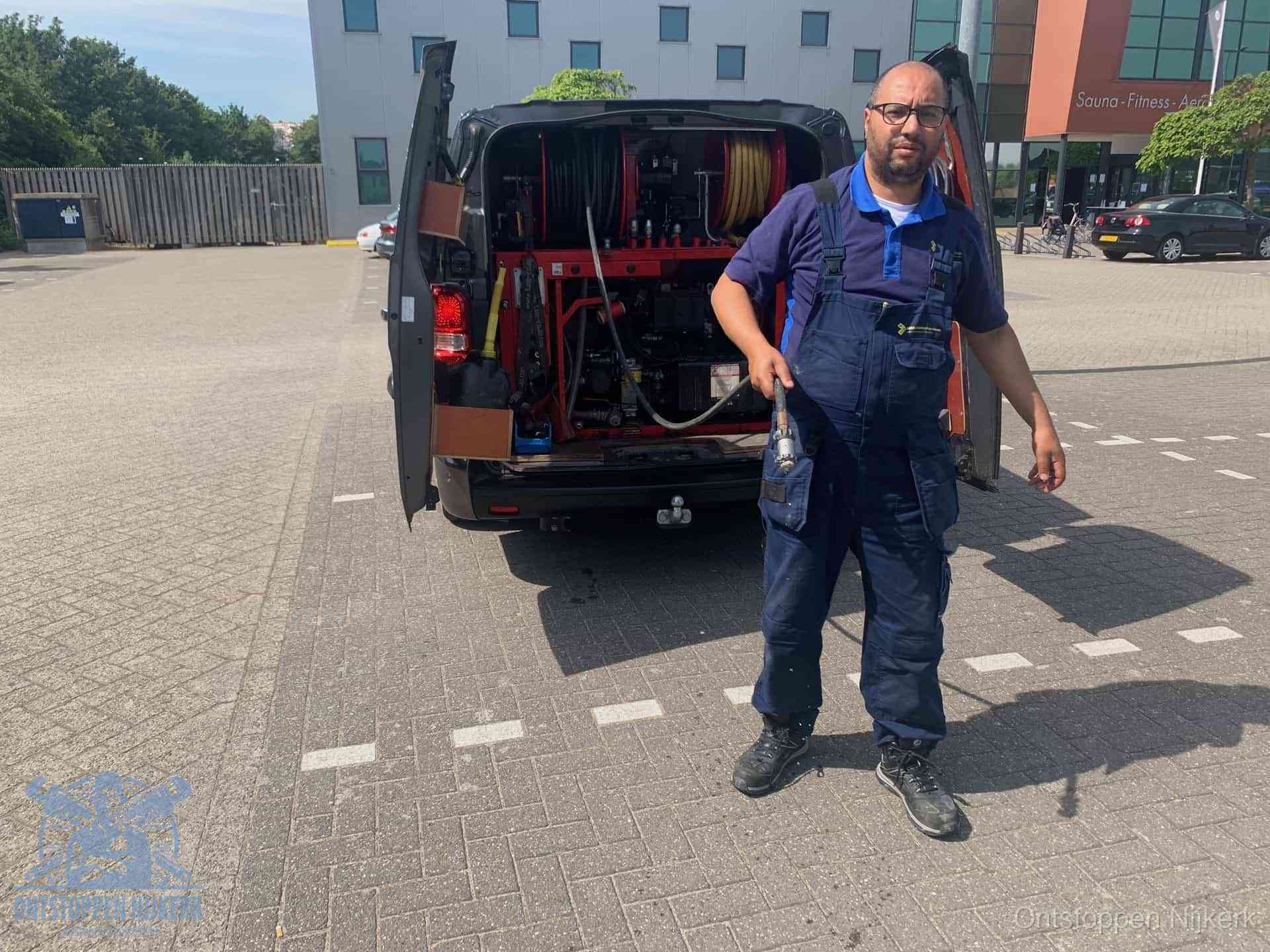 Een monteur bij zijn bestelbus met een hogedruk- en rioolreinigingsunit, klaar om de oorzaak van terugkerende wc-verstoppingen aan te pakken in Nijkerk