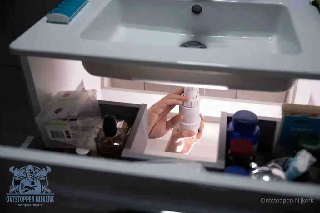 Een pompfles met zeep boven een wastafel in de toiletruimte, de warm water en afwasmiddel-methode om de wc te ontstoppen in Nijkerk