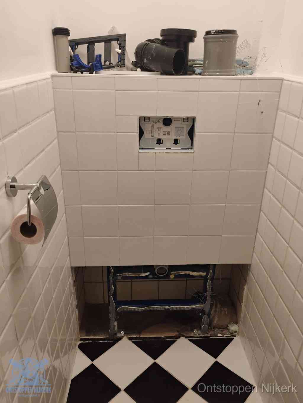 Een toiletruimte waar het hangtoilet en de inbouwreservoir-onderdelen zijn vrijgelegd voor onderhoud, periodiek nazicht voorkomt een wc-verstopping in Nijkerk